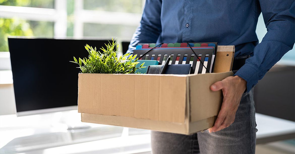 Ein Mann trägt einen Karton mit persönlichen Sachen als Symbol für Kündigen ohne neuen Job