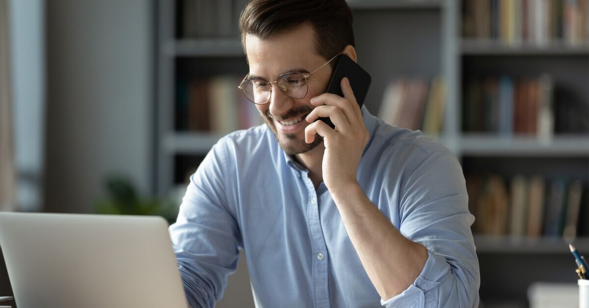 Ein Mann mit Handy am Ohr hat ein Telefoninterview für seine Bewerbung.